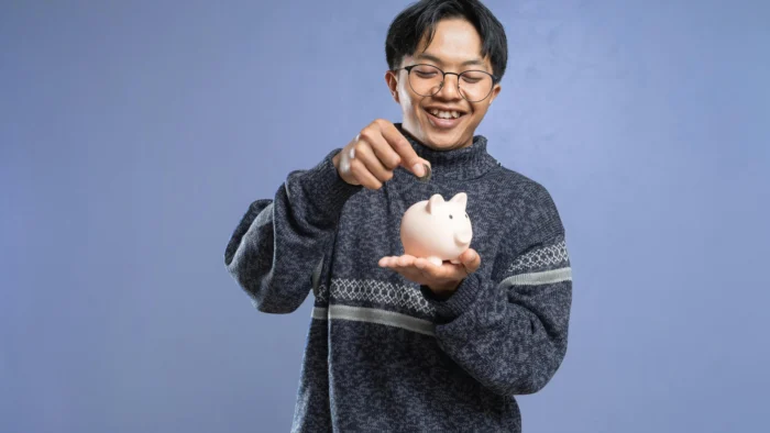 Man saving money in piggy bank for affordable Invisalign treatment