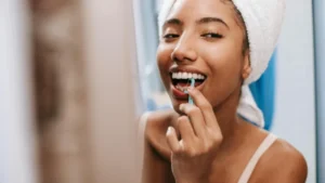 Woman using dental flosser, promoting clear aligners for crooked teeth