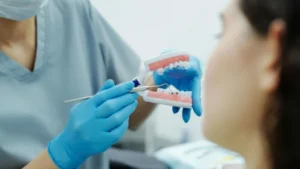 Dental professional in blue gloves demonstrating lingual wire braces to a patient